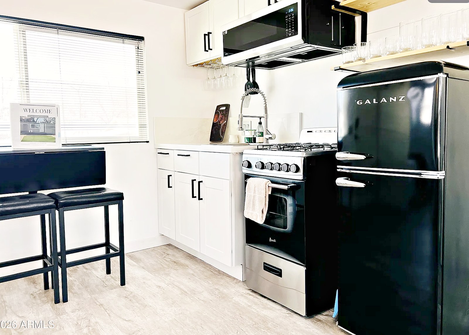 Kitchen with black refrigerator, stove and white cabinetry