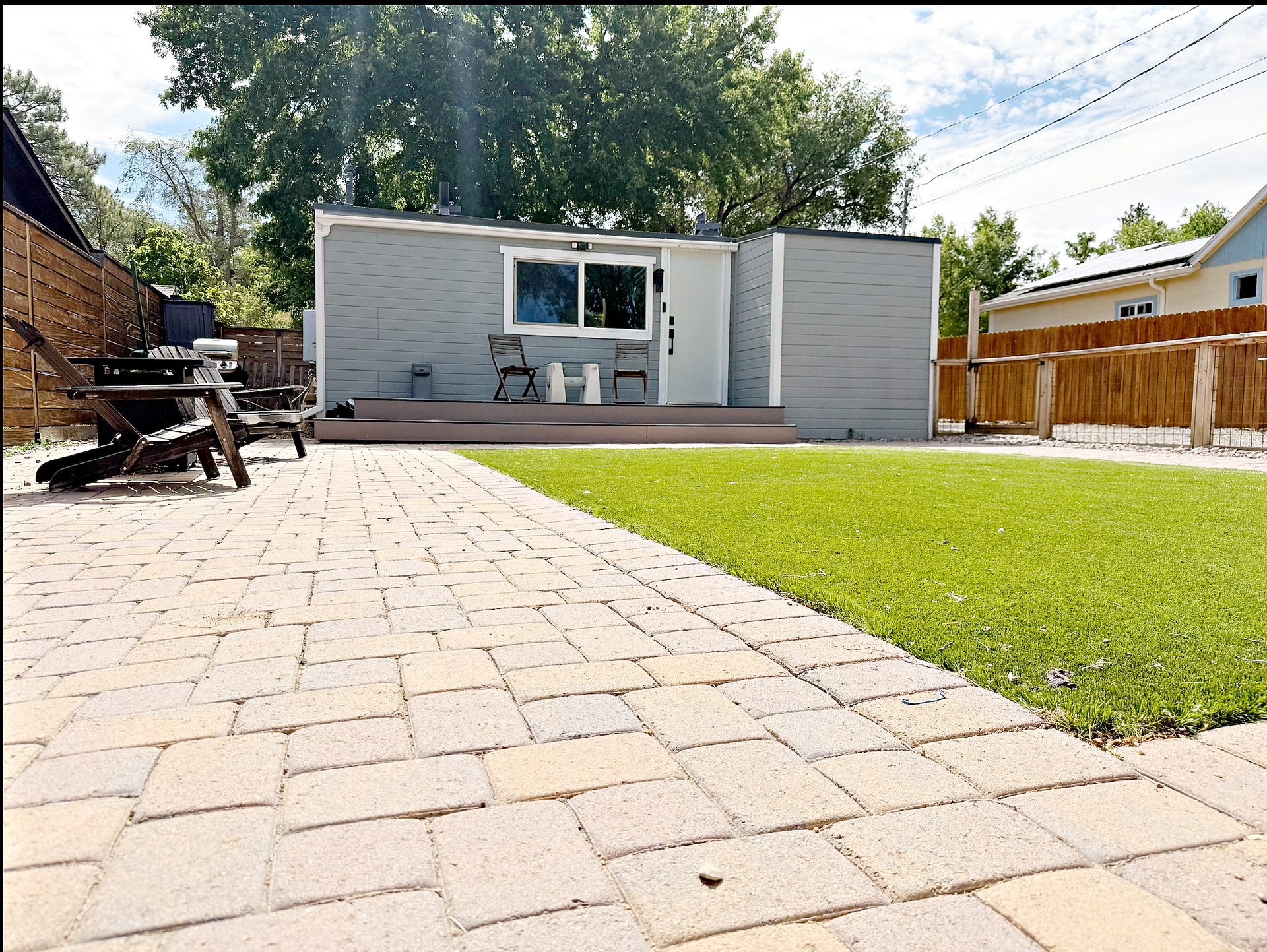 Low angle across the paver patio and artificial grass toward the home